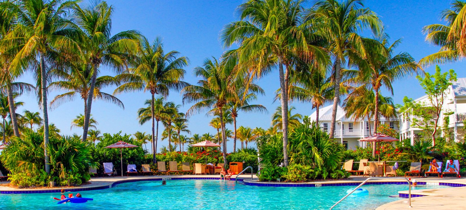 A Pool Next To A Body Of Water Surrounded By Palm Trees